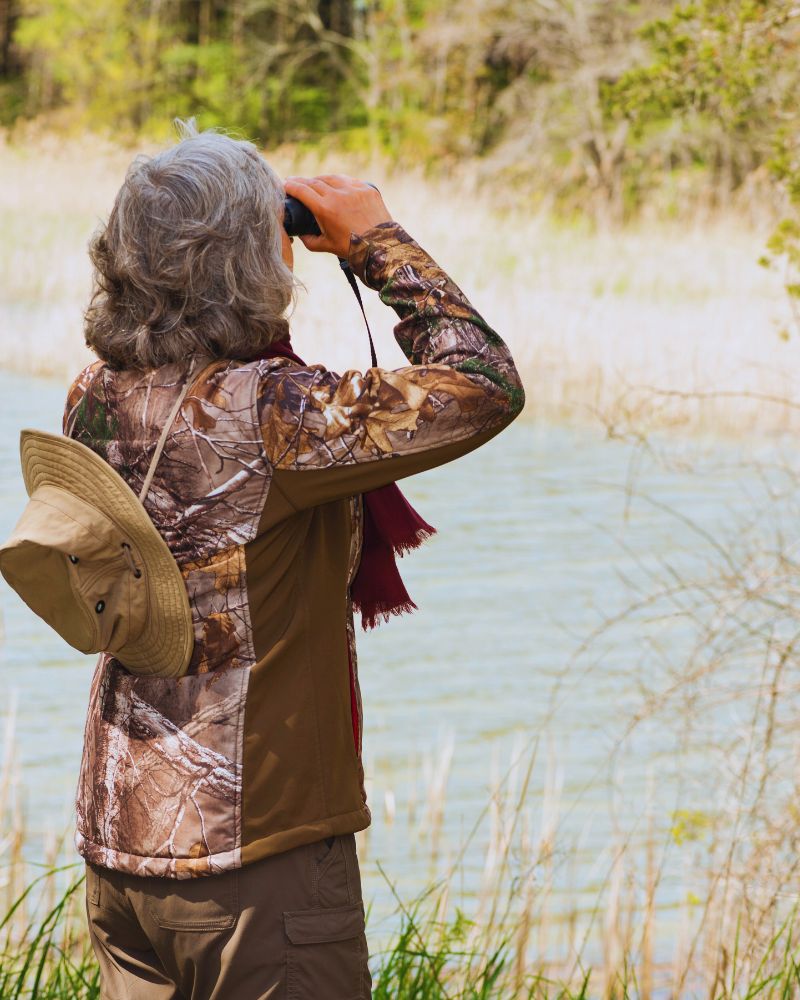 a woman looking through binoculars because she has taken up bird watching for couples over 50