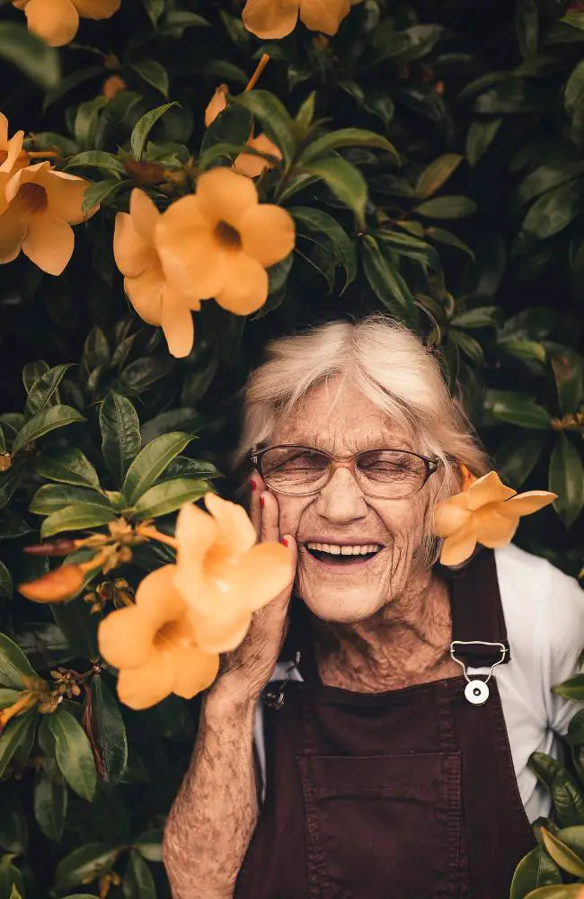 A woman smiling in front of flowers to show that there are many hobbies for people over 50.