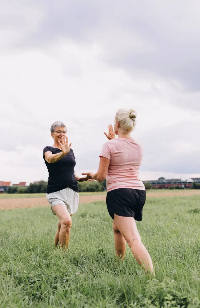 Two women practicing tai chi in a field to demonstrate one of the many hobbies for people over 50.