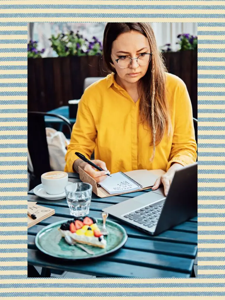 a woman sitting at a table with a laptop and a piece of food learning about the Upwork readiness test.