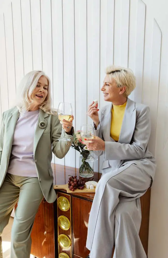 Wwo women holding wine glasses and smiling, happy to be engaged in wine making as one of the many hobbies available for people over 50.