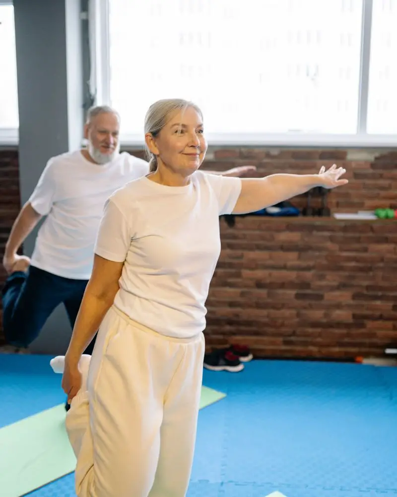 a woman and man doing yoga to demonstrate safe stretches for people over 50