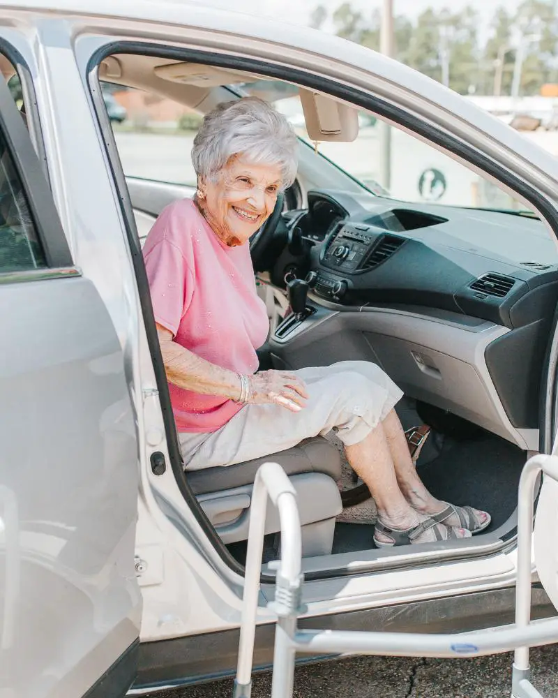 An elderly woman sitting in a car, waiting to be assisted by someone who started a transportation business as a great side hustle over 50.