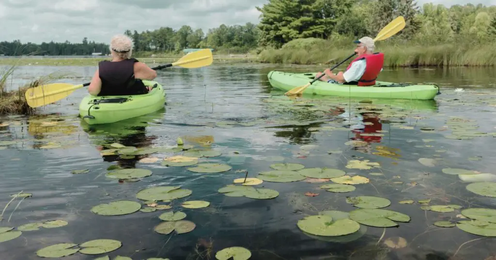 Two seniors in two green kayaks