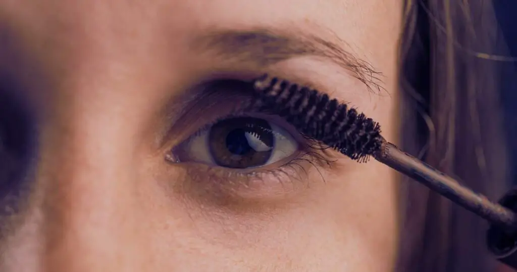 Woman applying mascara to show the best mascara products for over 50