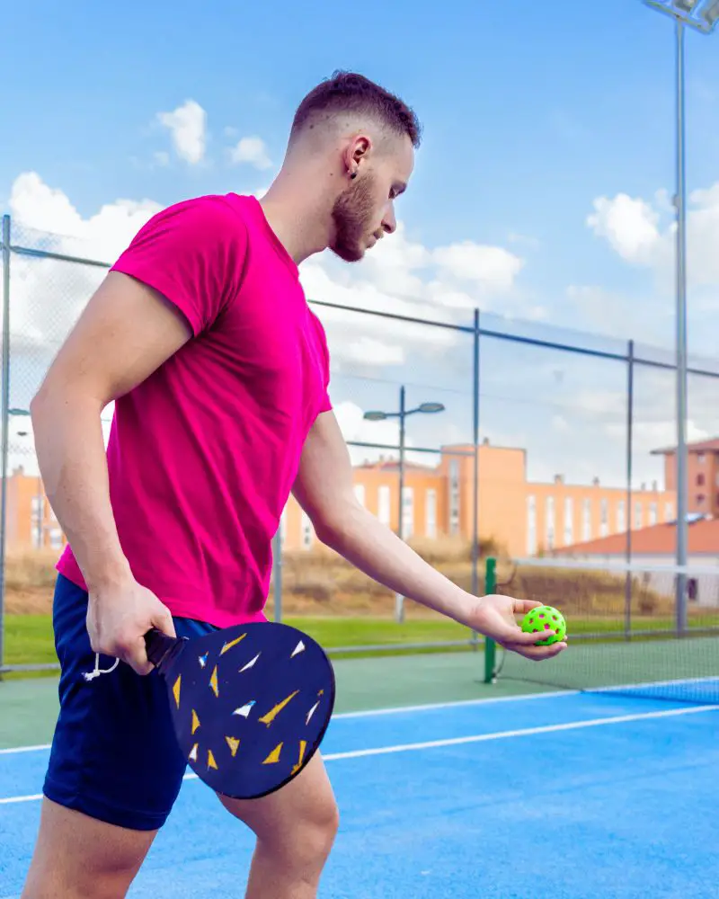 Male pickleball player in a pink shirt demonstrating good picketball etiquette