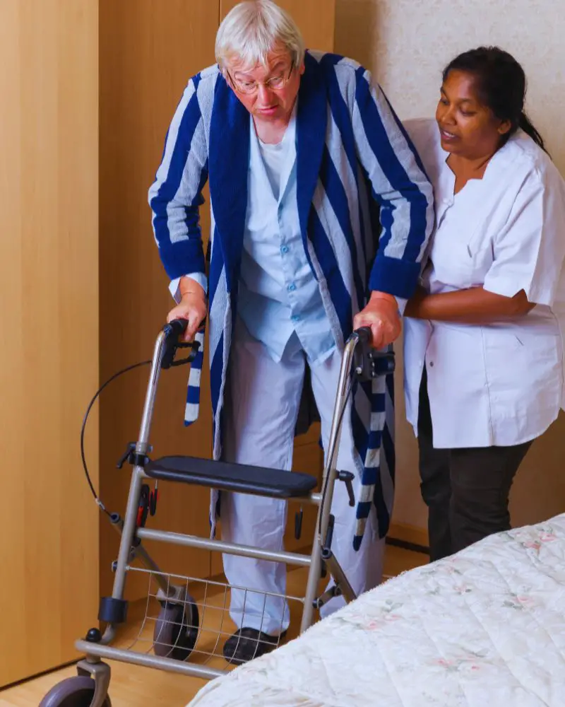 a nurse helping an old man with a walker to the shower to help answer the question how often should the elderly shower