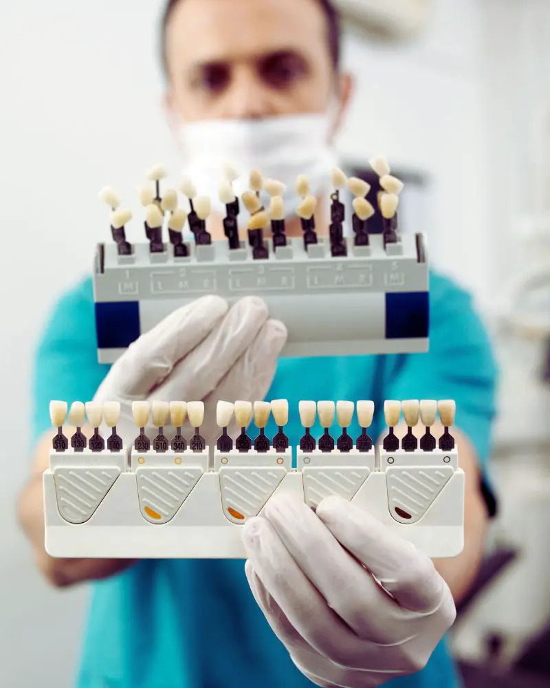 a person holding a rack of teeth to show different color options and to help answer the question of whether veneers are bad for your teeth