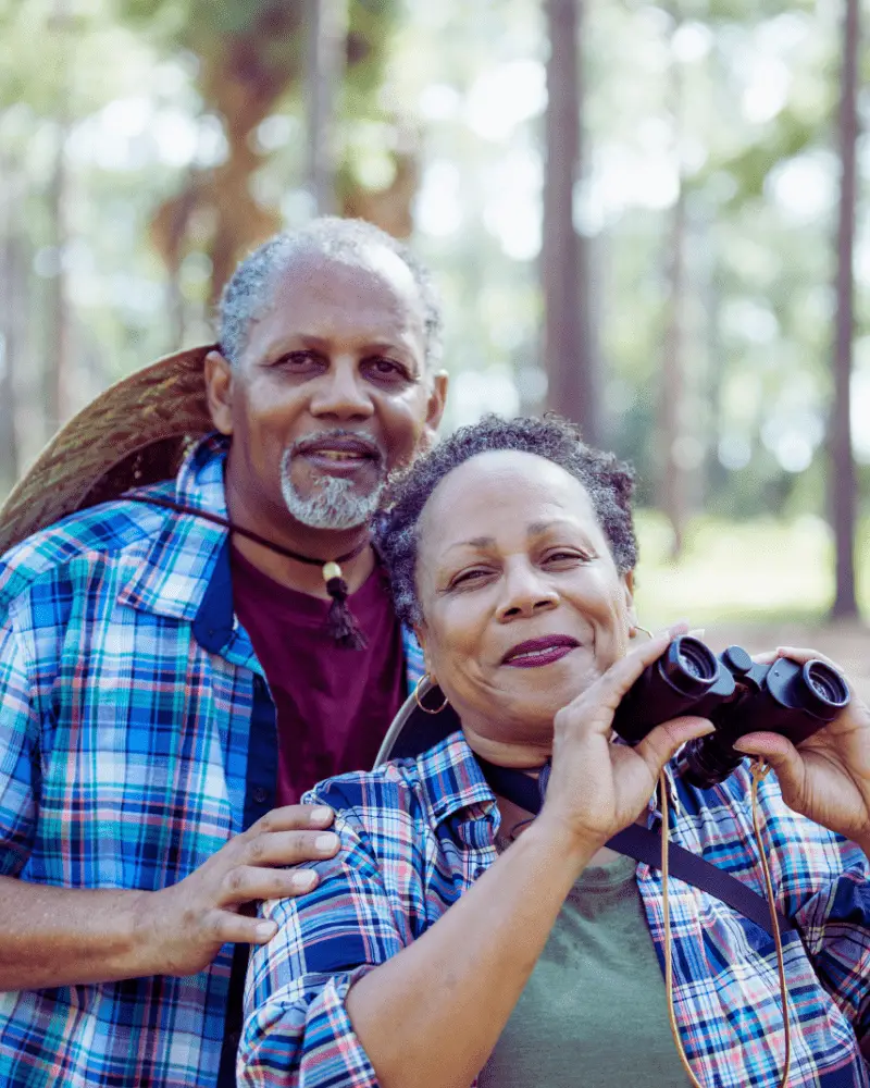 a man and woman holding binoculars to go bird watching for couples over 50