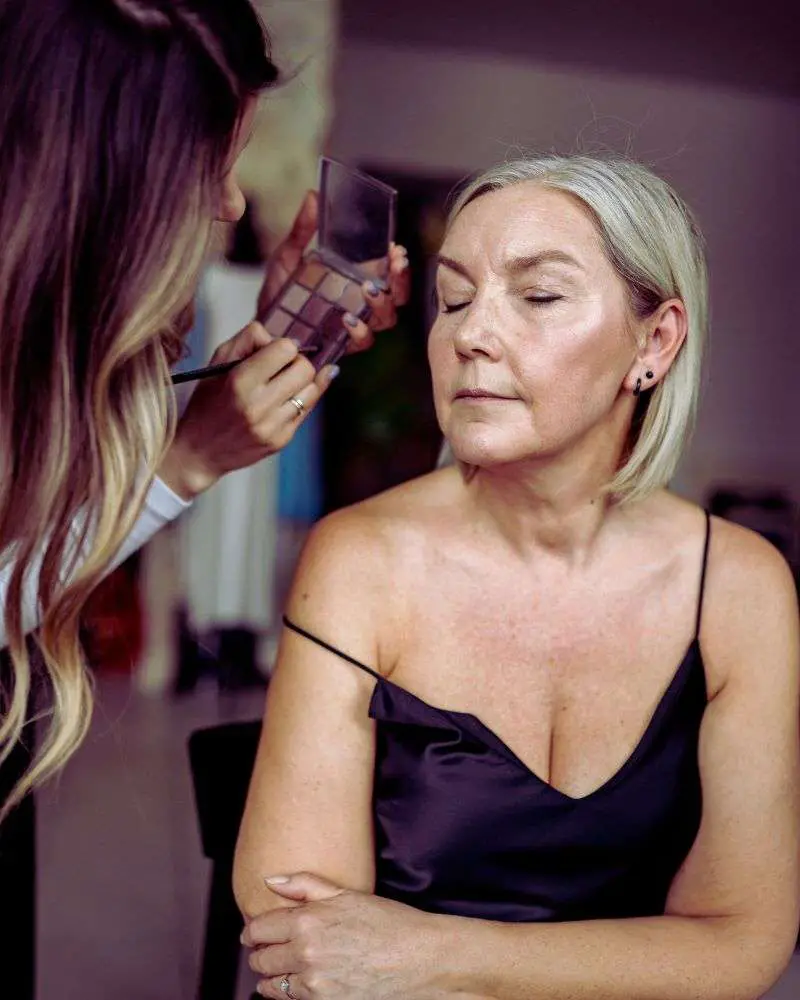 a woman getting her makeup done after getting advice from beauty bloggers over 50