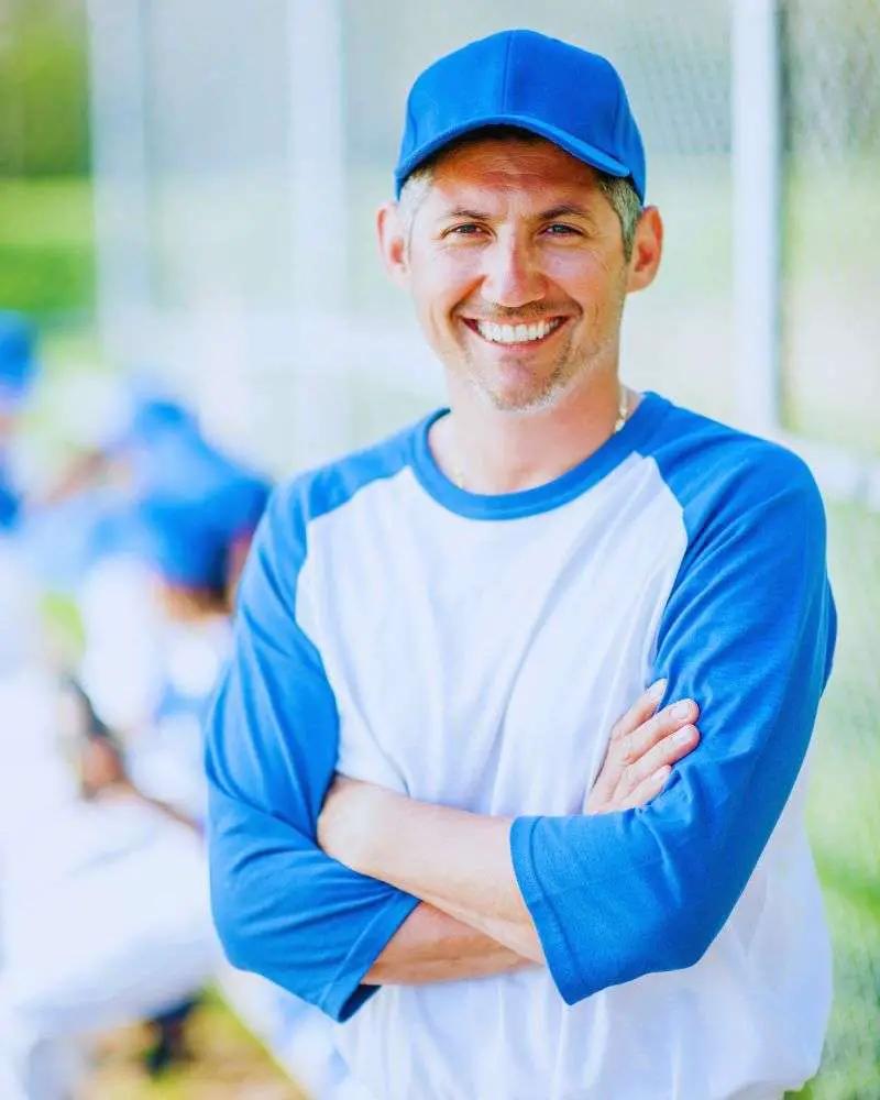 a man wearing a baseball cap and smiling because he tried out for over 50 baseball leagues