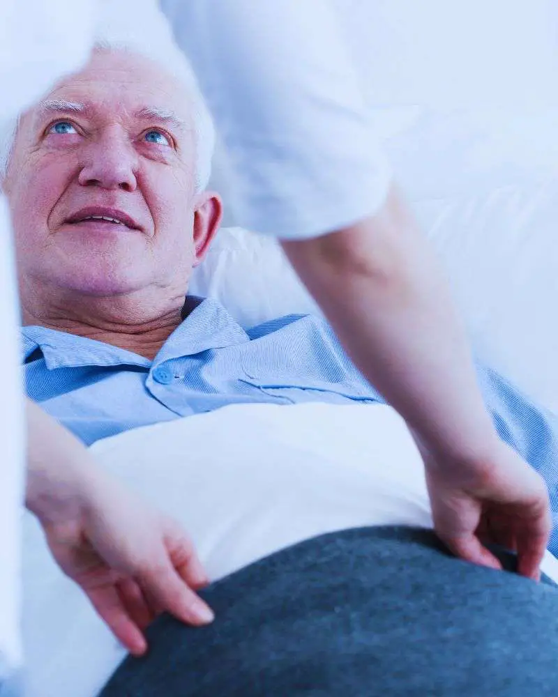 a man lying in bed with a nurse touching his stomach while his family is likely asking how-long-do-hospice-patients-live-without-eating