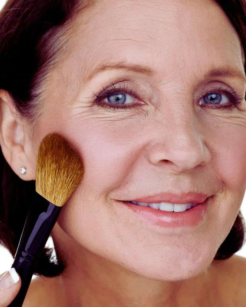 a woman with a makeup brush ready to put her skills into action after reading beauty bloggers over 50