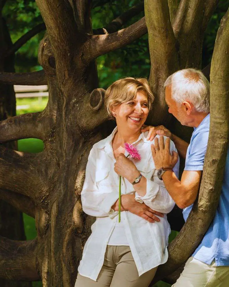 a man holding a flower next to a woman who is wondering how to know if a man over 50 likes you.