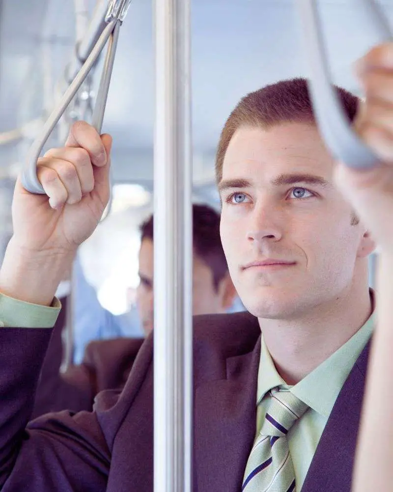 a man holding a handle on a bus after considering the pros and cons of not renewing your driver's license