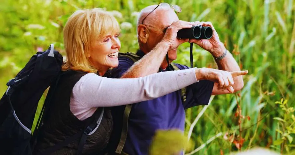 a man and woman looking through binoculars because they are birdwatching couples over 50