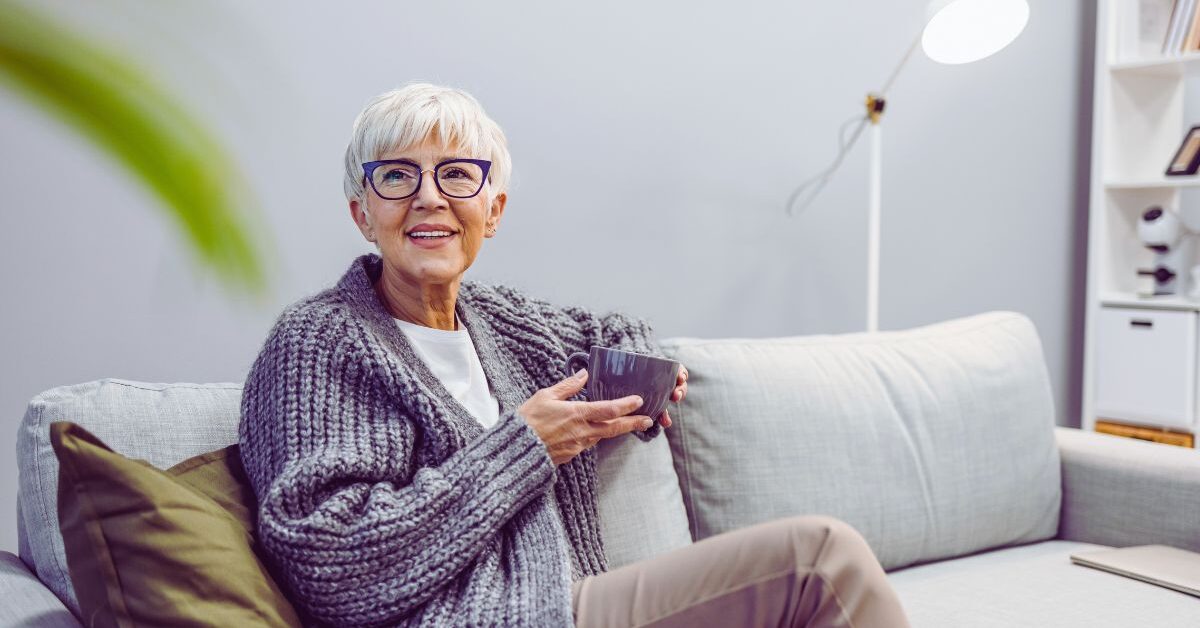 a woman sitting on a couch holding a cup in a pose that demonstrates what it's like modelling over 50