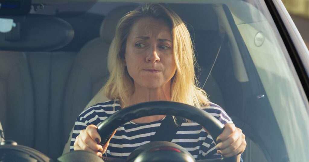 a woman who is over 50 and afraid to drive holding a steering wheel