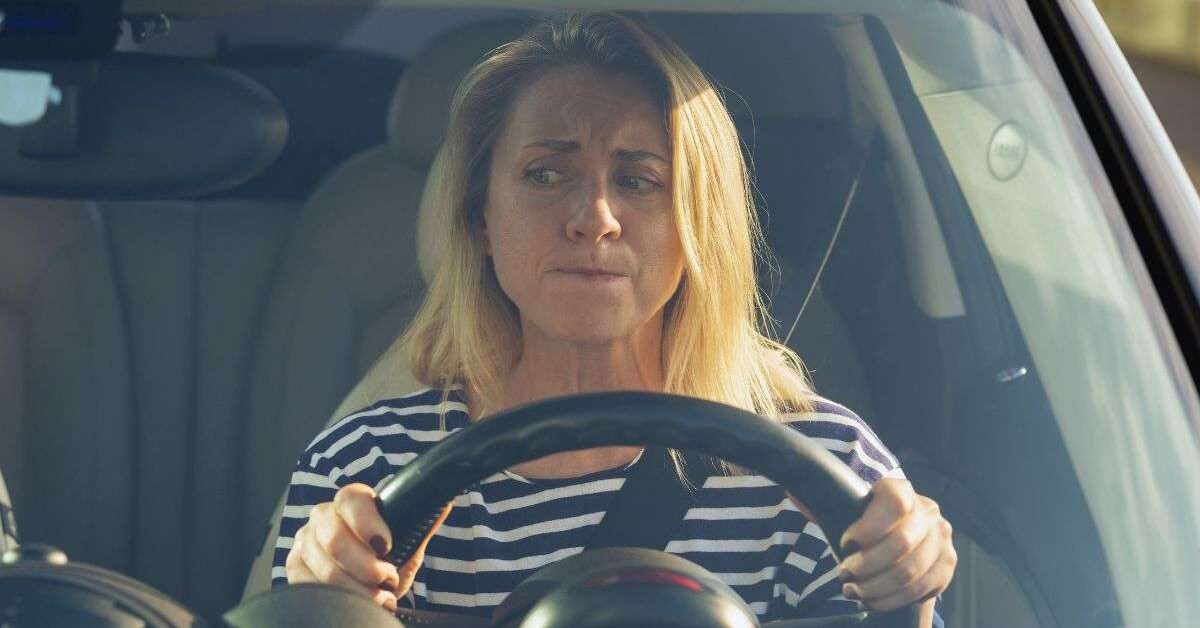 a woman who is over 50 and afraid to drive holding a steering wheel