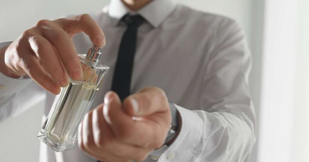 Man with a white shirt and tie applying cologne to his wrist