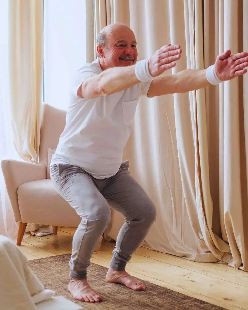 a man squatting on a mat doing chair pose to demonstrate yoga for couples over 50