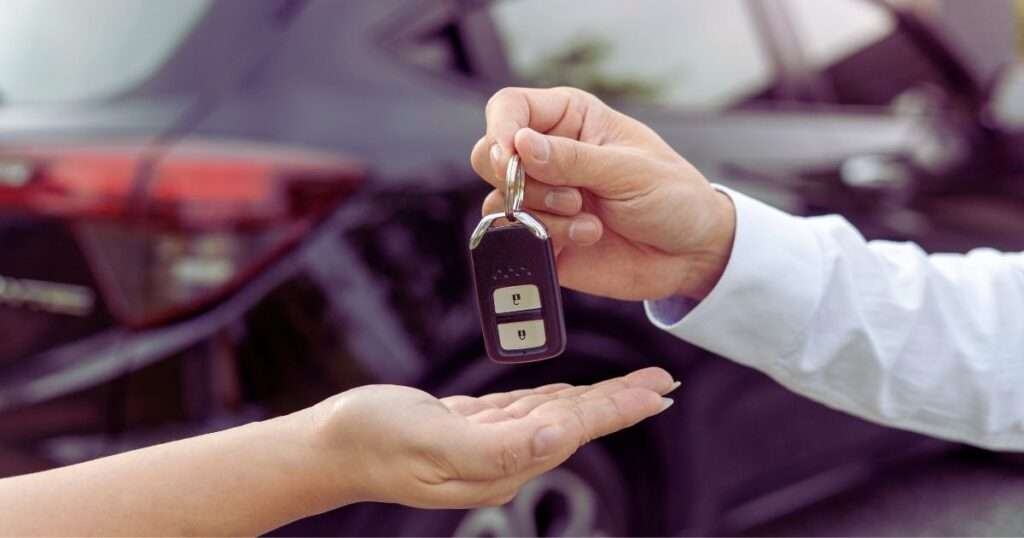 a person handing over a car key after weighing the pros and cons of not renewing driver's license