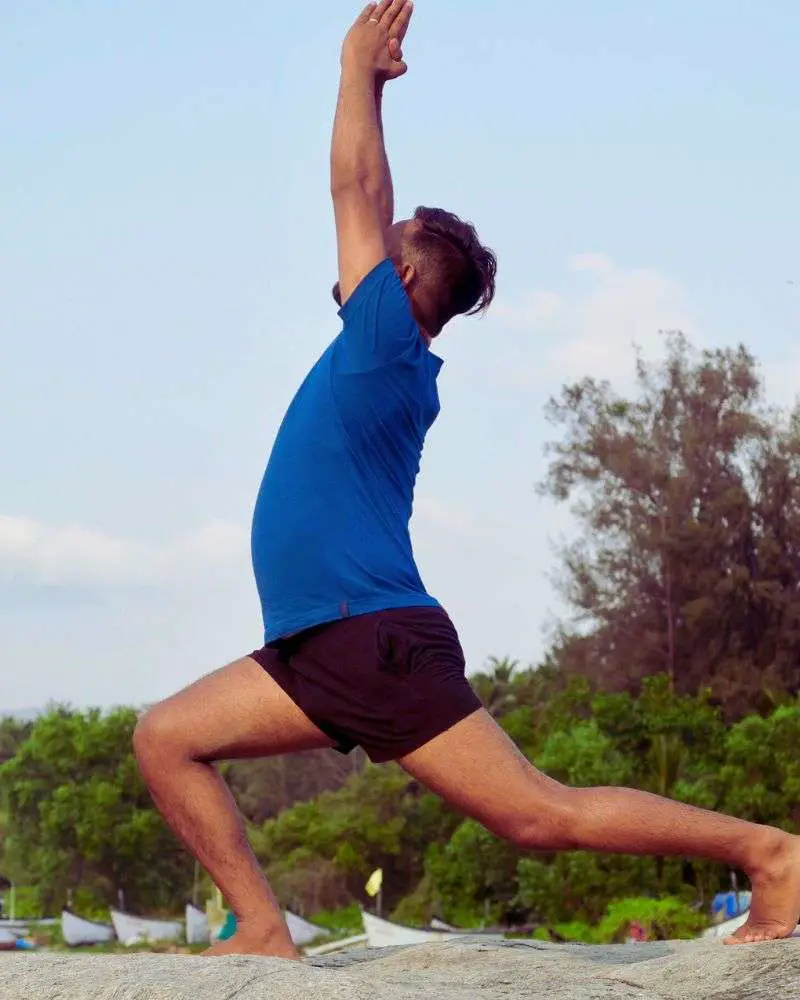 a man in blue shirt and black shorts jumping in the air with his arms up