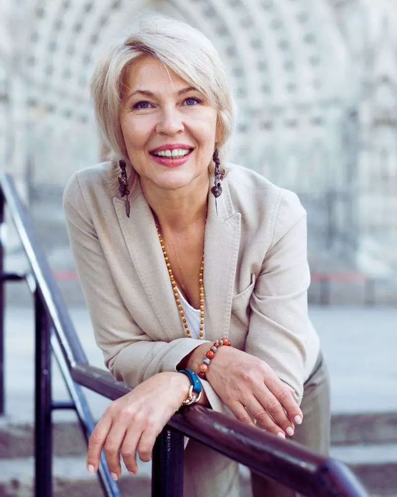 a woman leaning on a railing with clothing that demonstrates the best petite women's fashion over 50.