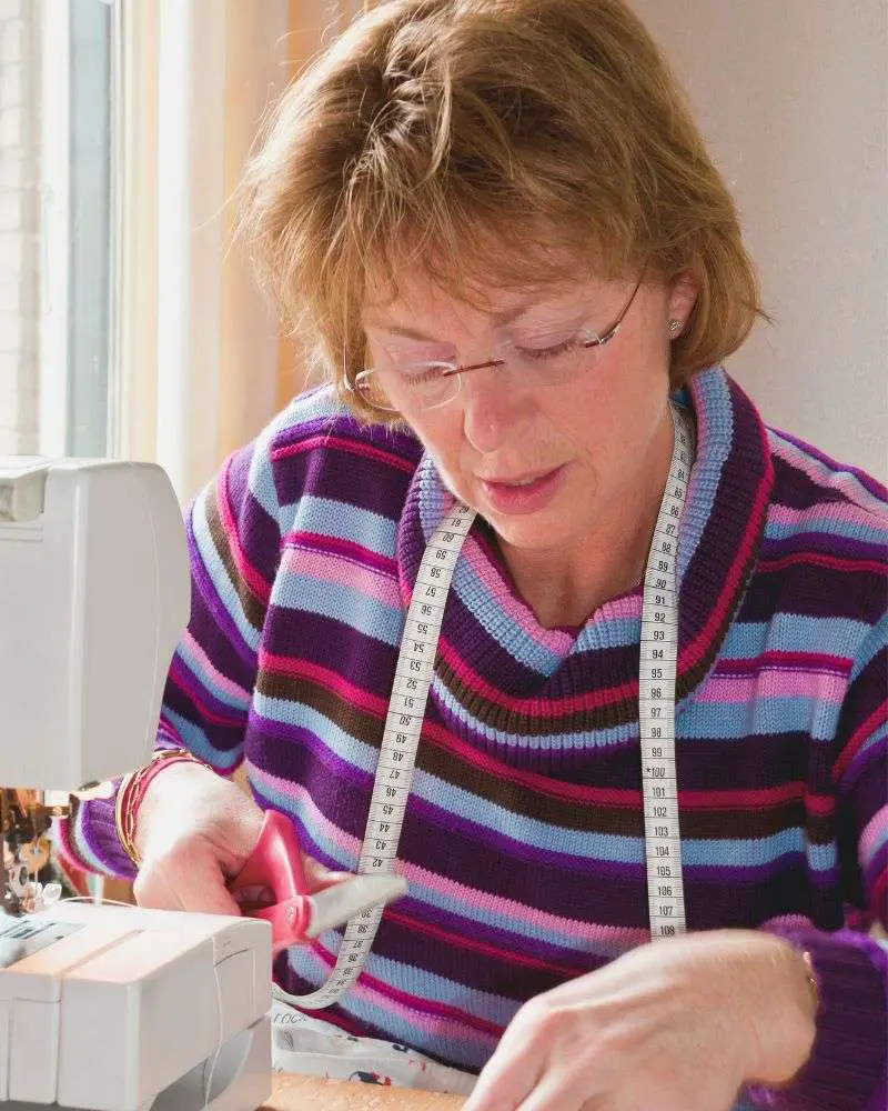 a woman using a sewing machine after reading 19-best-sewing-blogs-for-over-50