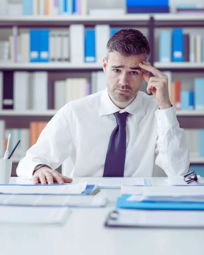 a man sitting at a desk with his hand on his head considering second careers for lawyers over 50