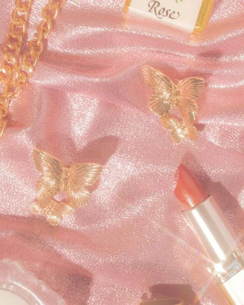 a lipstick and earrings on a pink fabric