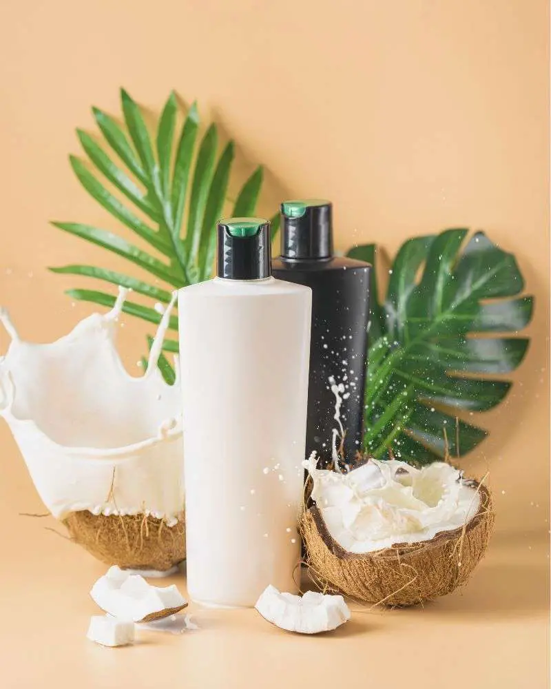 Two product bottles next to a cracked open coconut to demonstrate best-shampoo-and-conditioner-for-hair-over-50