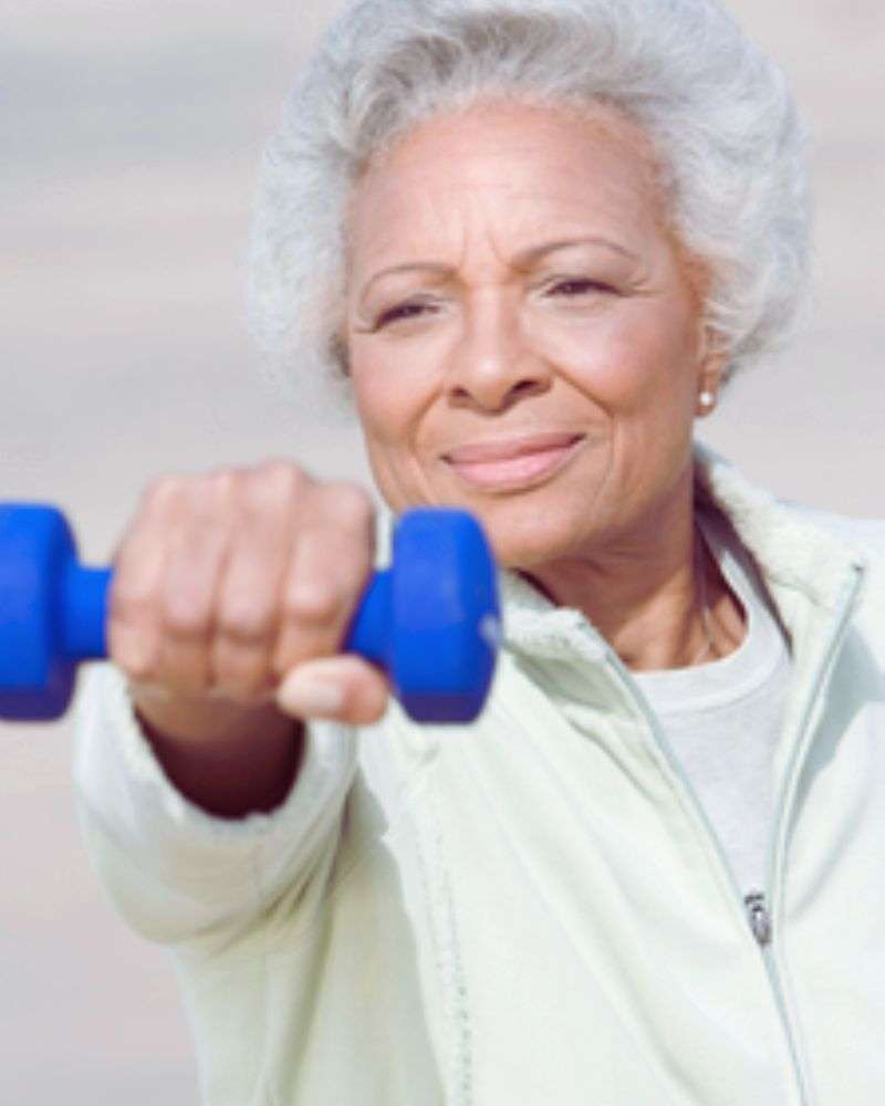 White haired women doing a single raise with a barbell to demonstrate safe 5x5 workouts for over 50 women