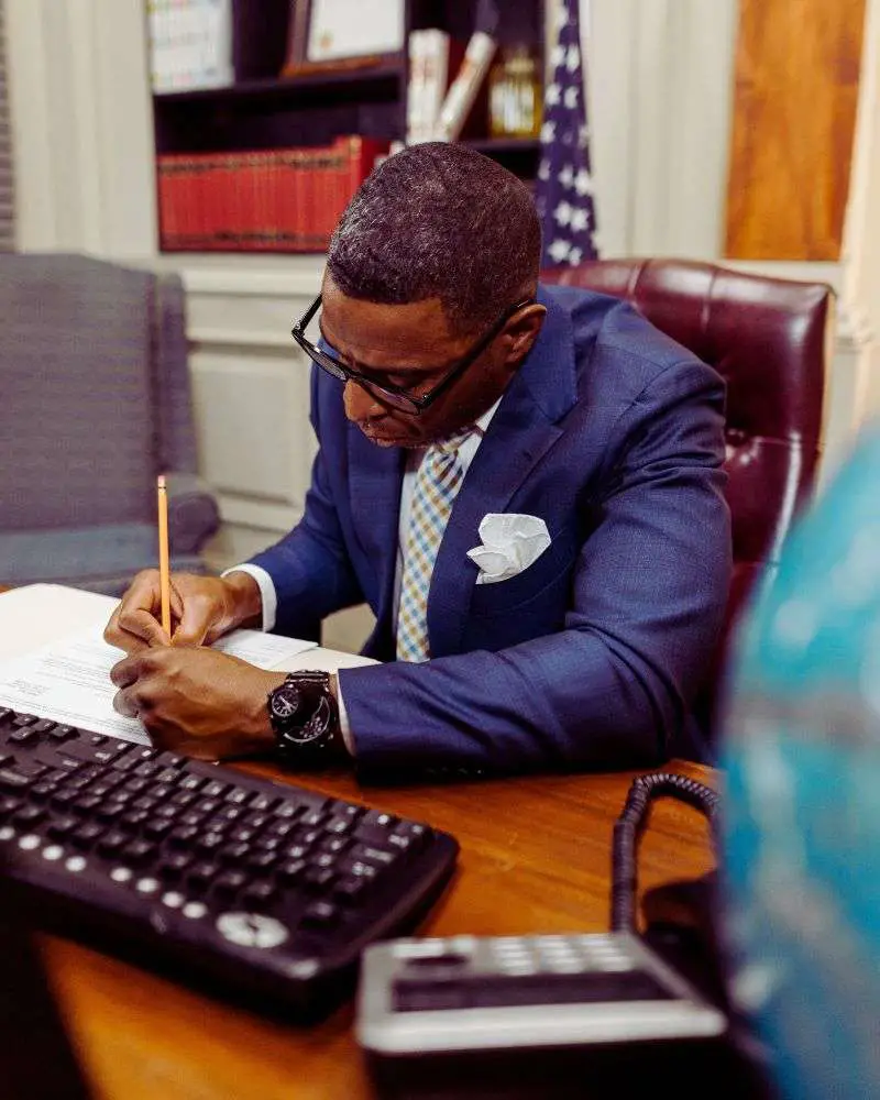 a man sitting at a desk writing on a piece of paper after considering second careers for lawyers over 50