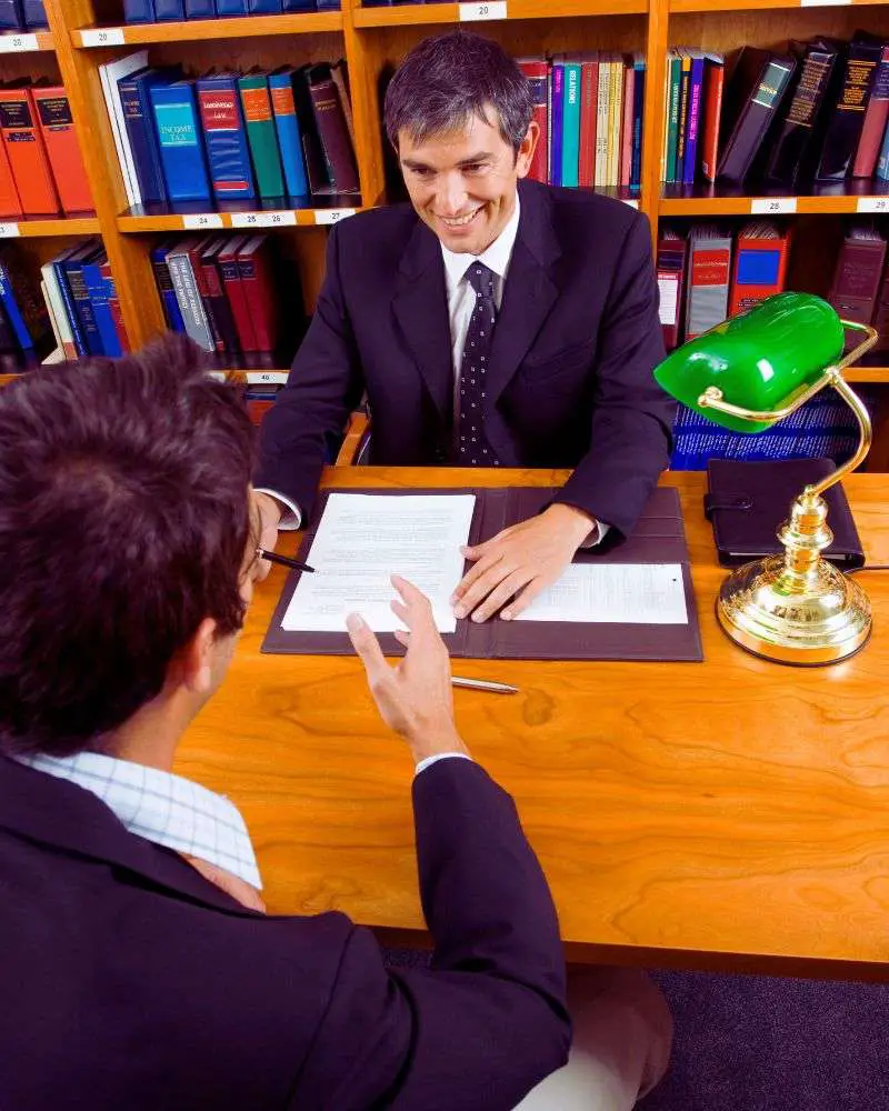 a man in a suit and tie sitting at a desk with a man in a suit and tie