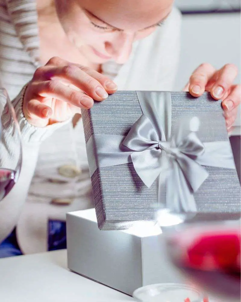 a woman opening a gift box from someone who read  best gifts for women over 50