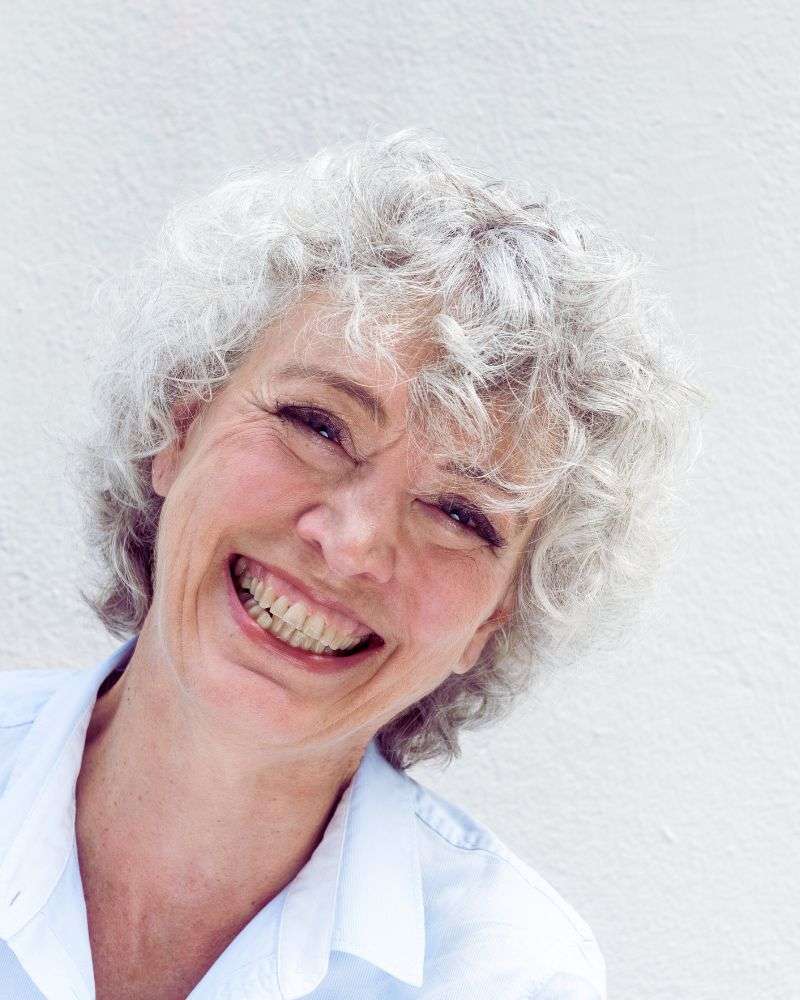 a woman with white hair smiling because she knows the benefits of botox