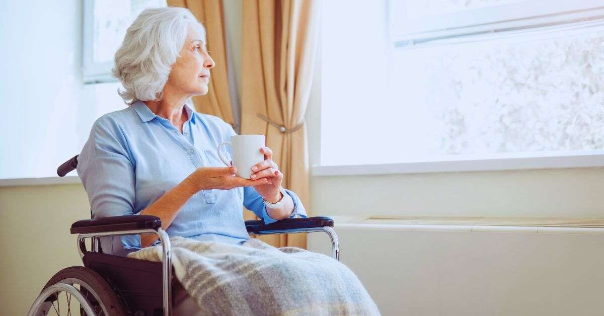 a woman in a wheelchair holding a cup to demonstrate one of many mobility devices for seniors