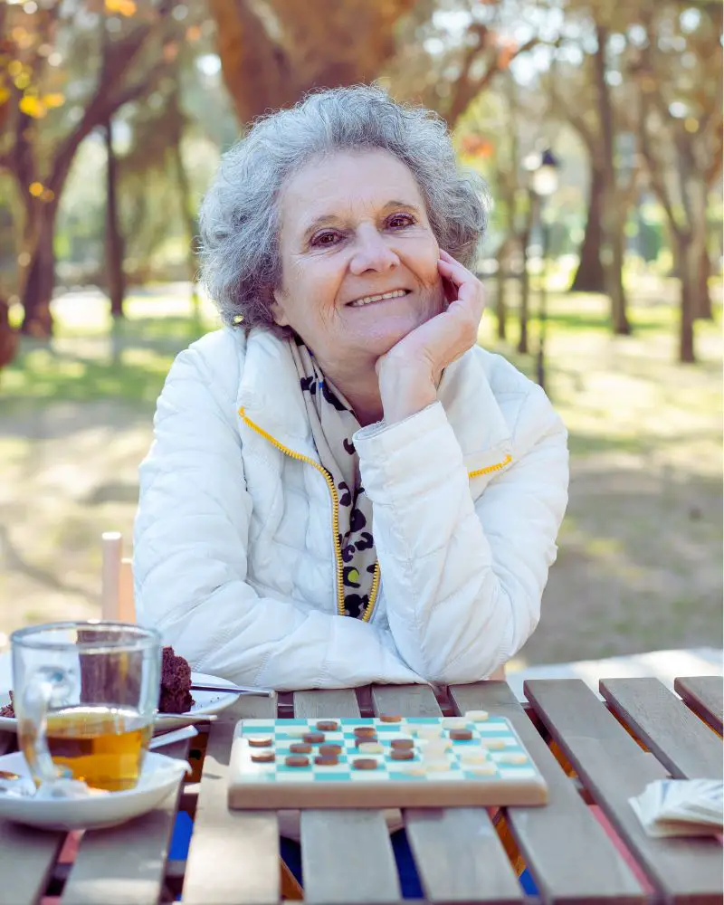 a woman sitting at a table with a checkerboard and a cup of tea