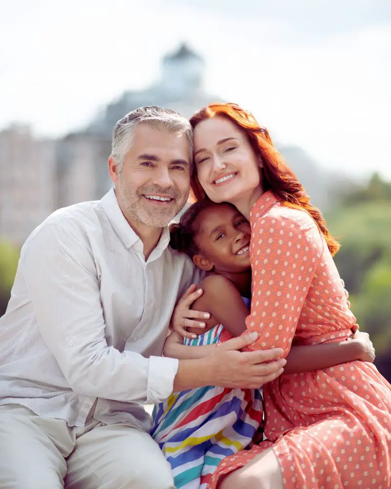 a man and woman hugging a girl after considering foster-parenting-over-50