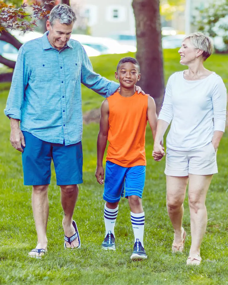 a man and woman holding hands and walking with a boy after considering foster-parenting-over-50