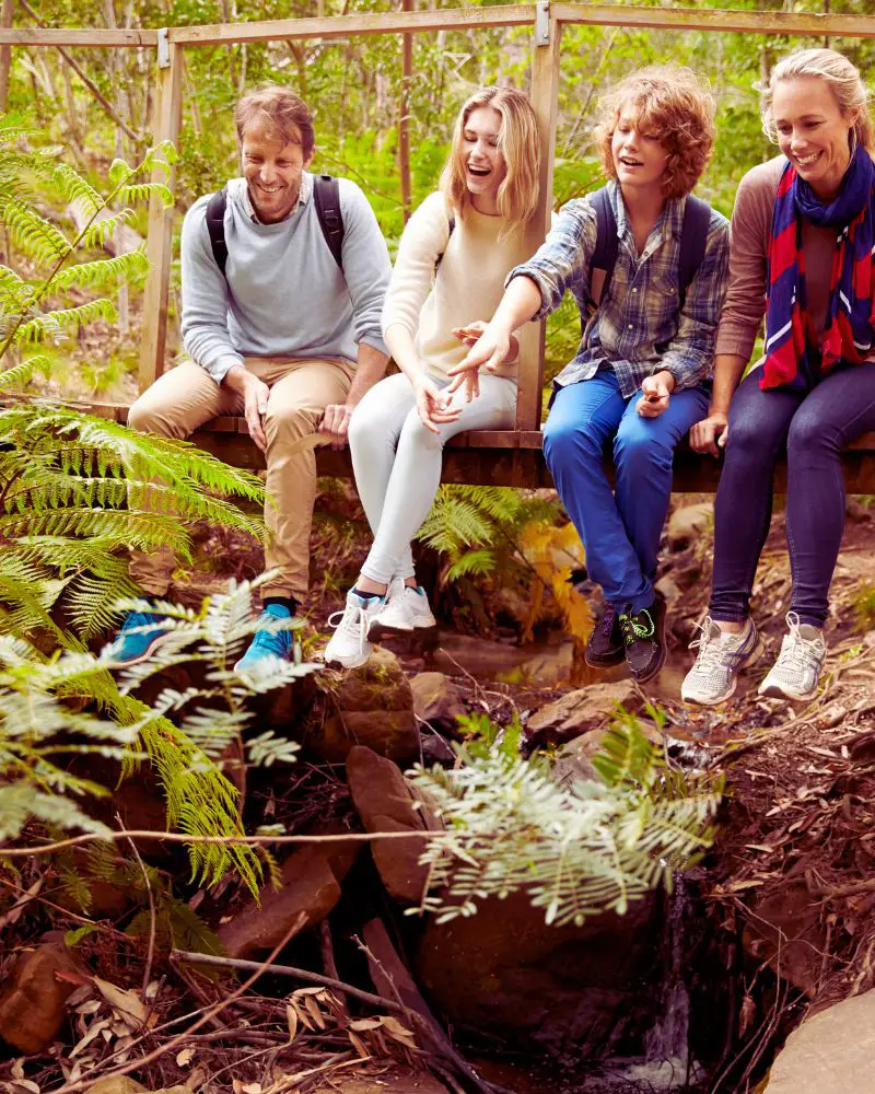 a group of people sitting on a bridge talking with their children after considering foster-parenting-over-50