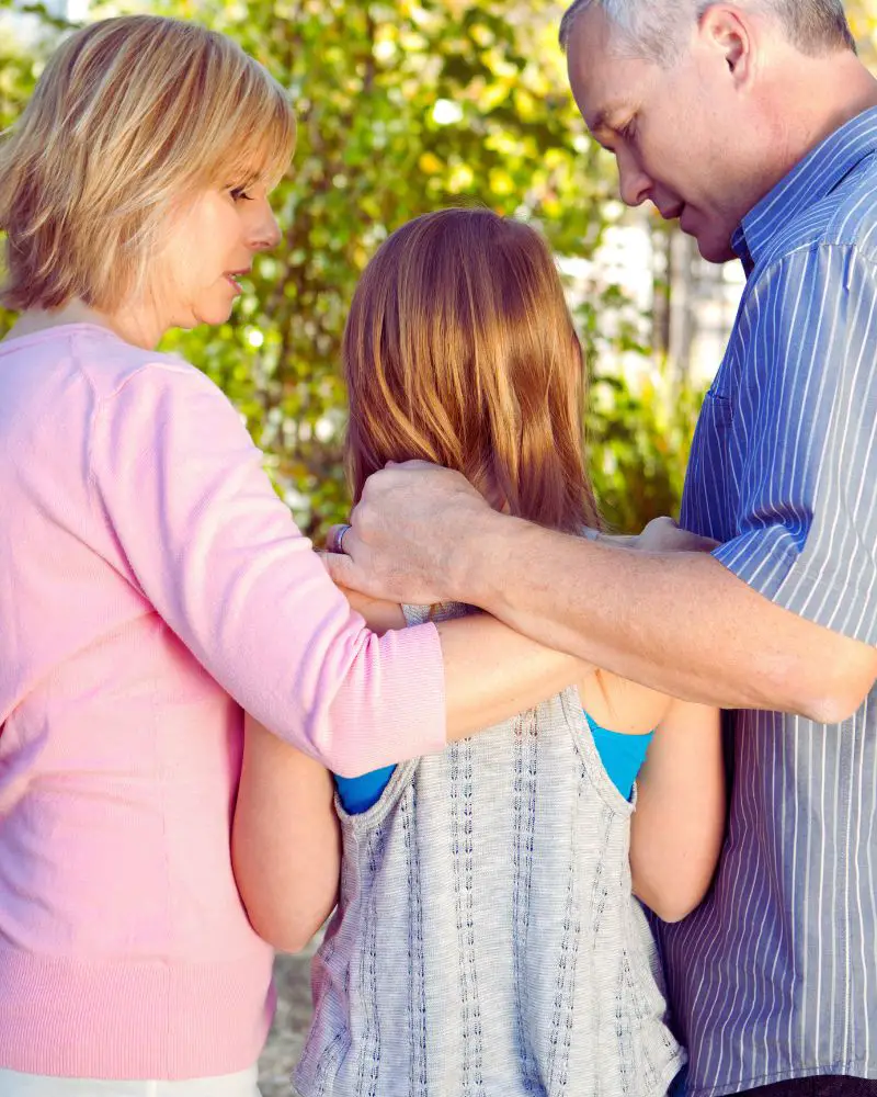 a man and woman standing outside with a girl talking to her about foster parenting over 50