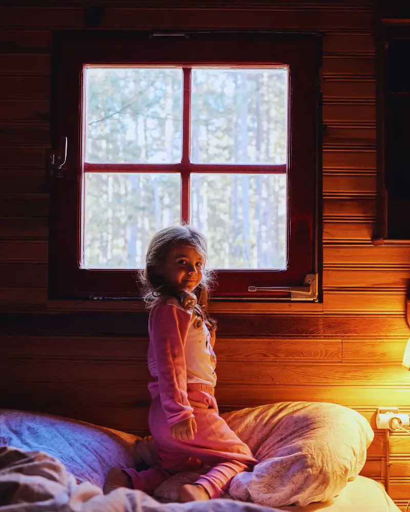 a girl sitting on a bed in a cabin to convey cabin quotes for instagram