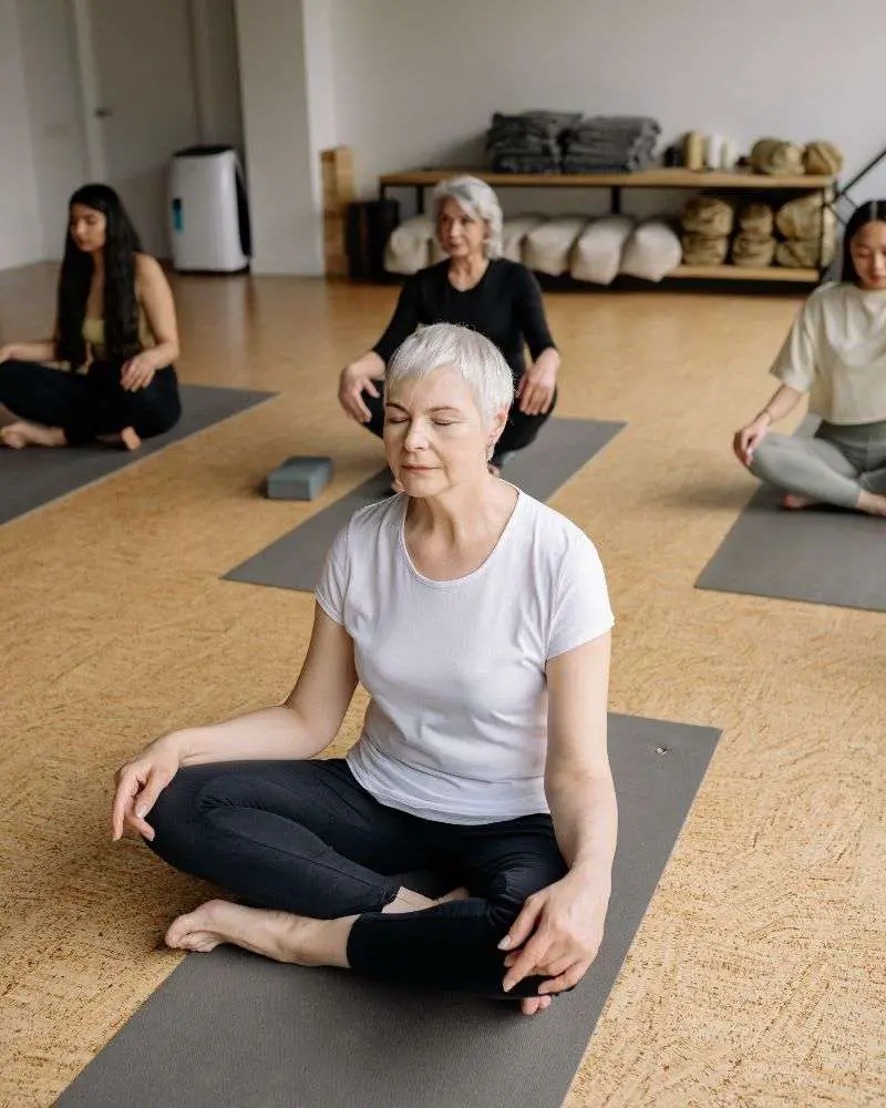 a group of women sitting on mats in a room with yoga mats practicing the best yoga dvds for beginners over 50