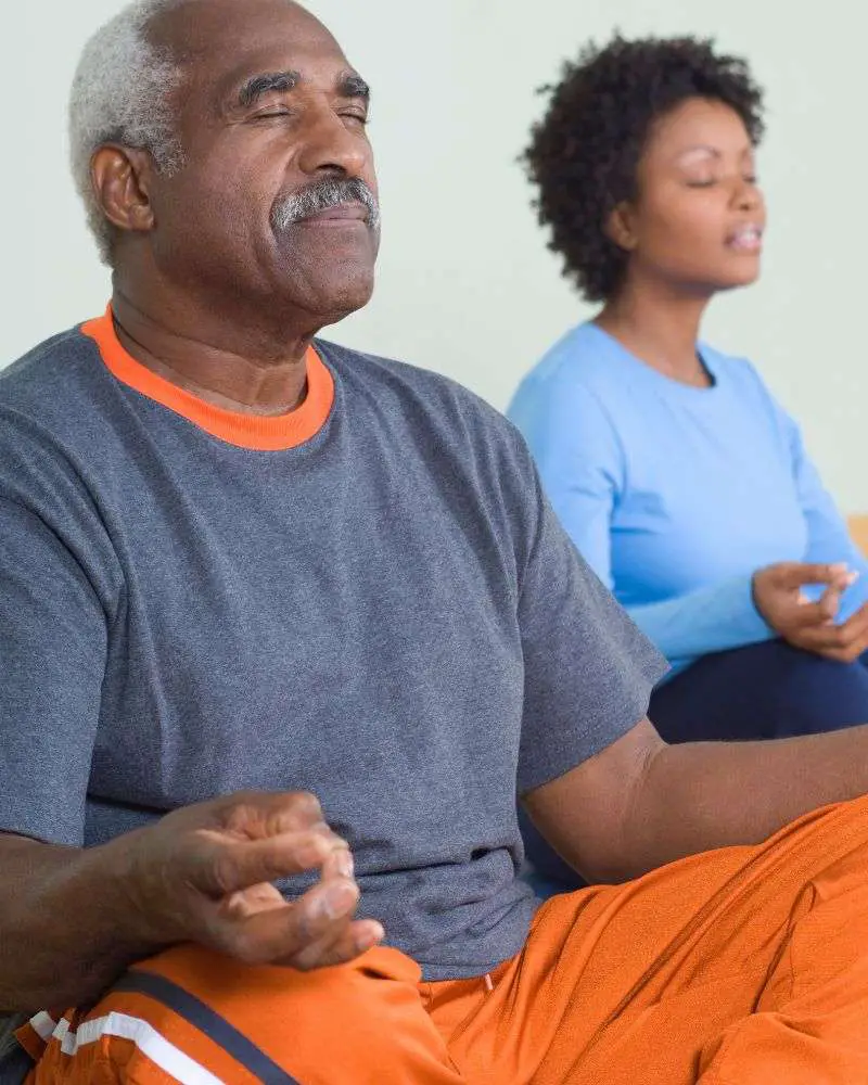 a man and woman meditating while practicing one of the best yoga dvds for over 50