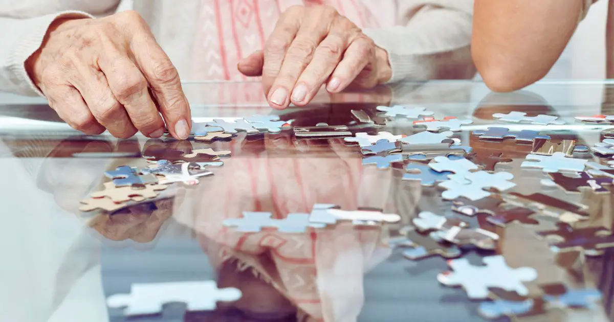 hands holding a puzzle on a table after learning how to create your own memory games