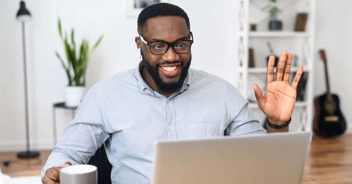 a man waving at a laptop after learning how to become a life coach over 50