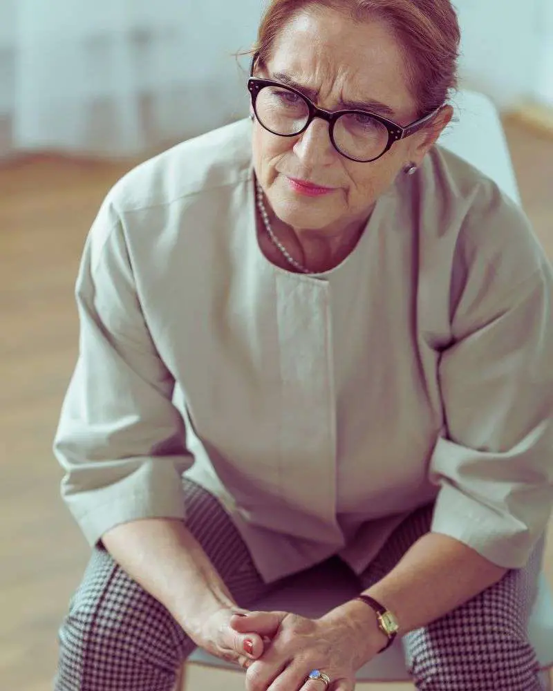 a woman sitting down with her hands clasped