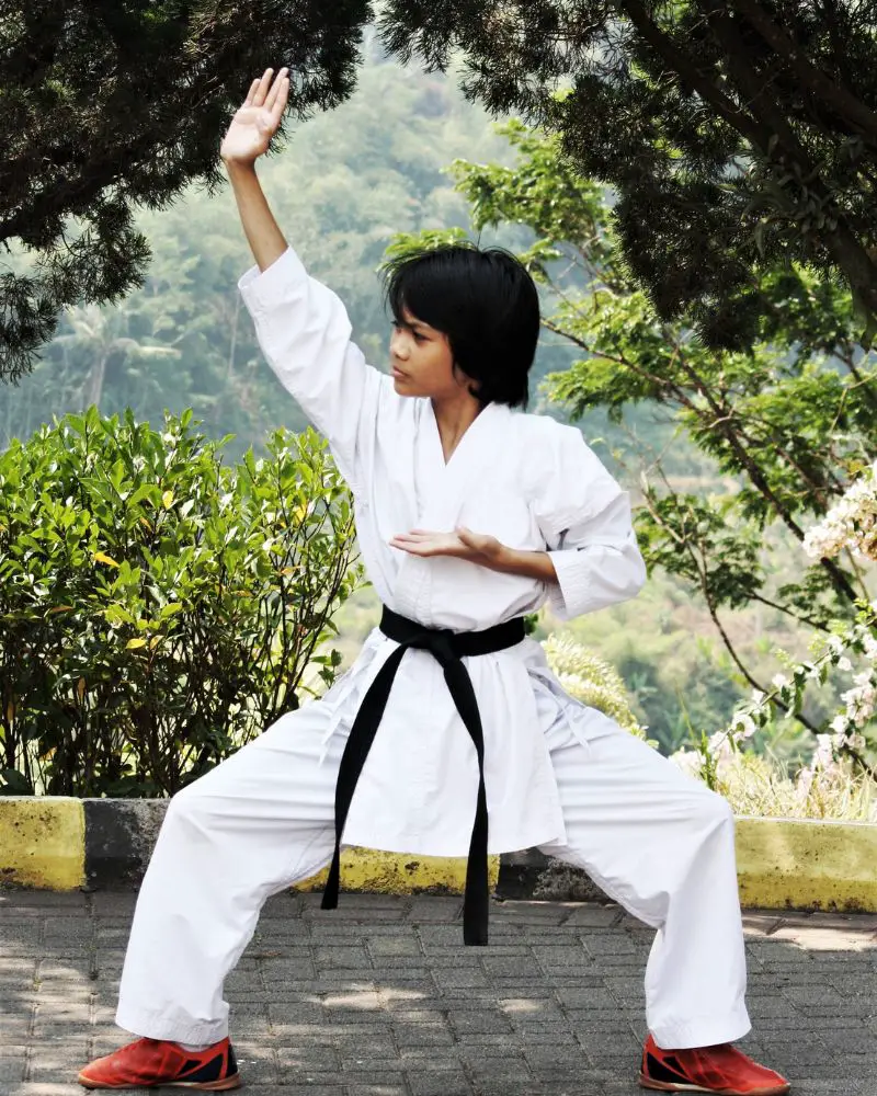 a person in a white uniform with a black belt performing martial arts for people over 50